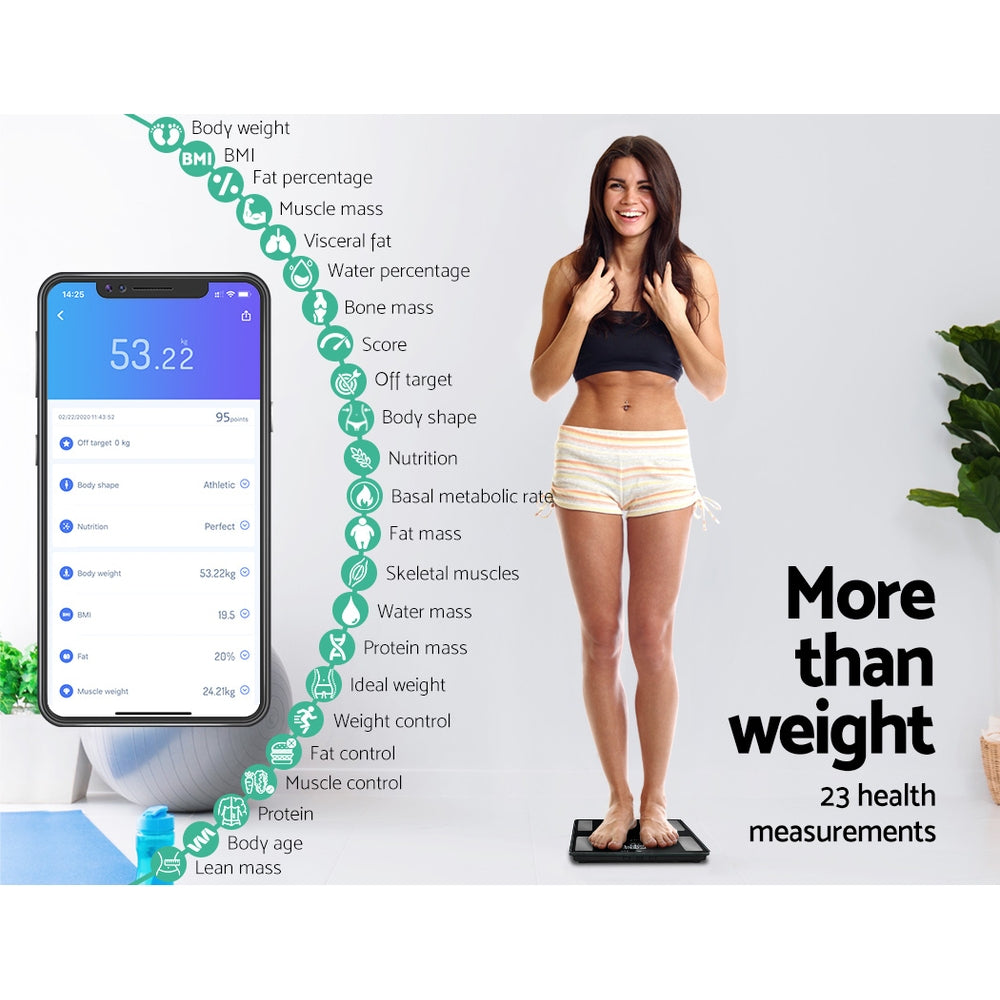 Smiling Lady in shorts and black top standing on bathroom scales with mobile phone displaying apptext reads More than weight 23 health measurements.