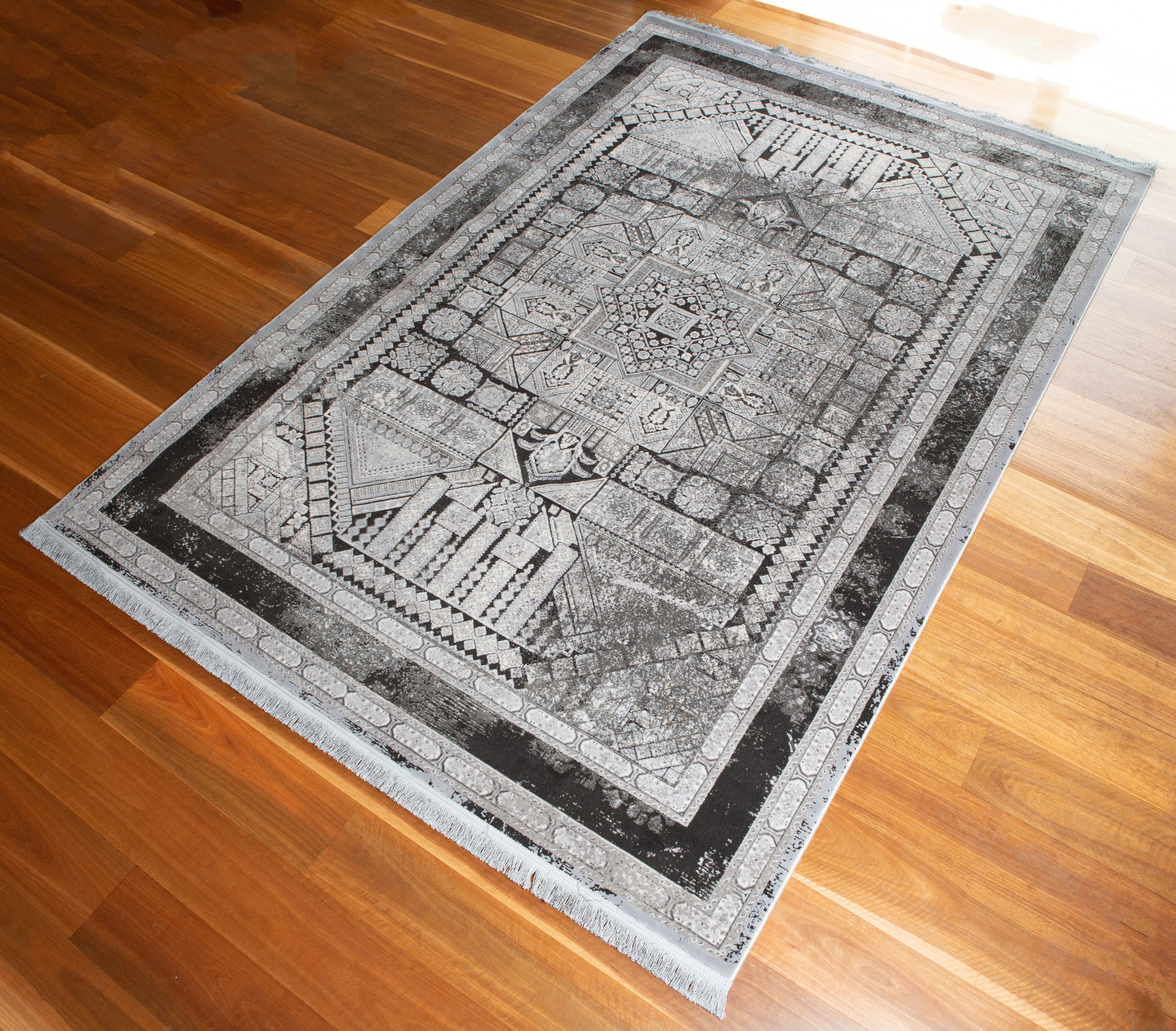 Persian floor rug light grey and Black geometric tree of life styled design on a wood panel floor.