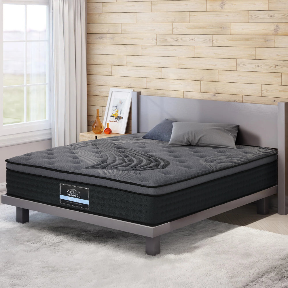 A soft charcoal grey and black mattress on bed frame with shagpile rug and wood lined back wall very cosy and opulent. 